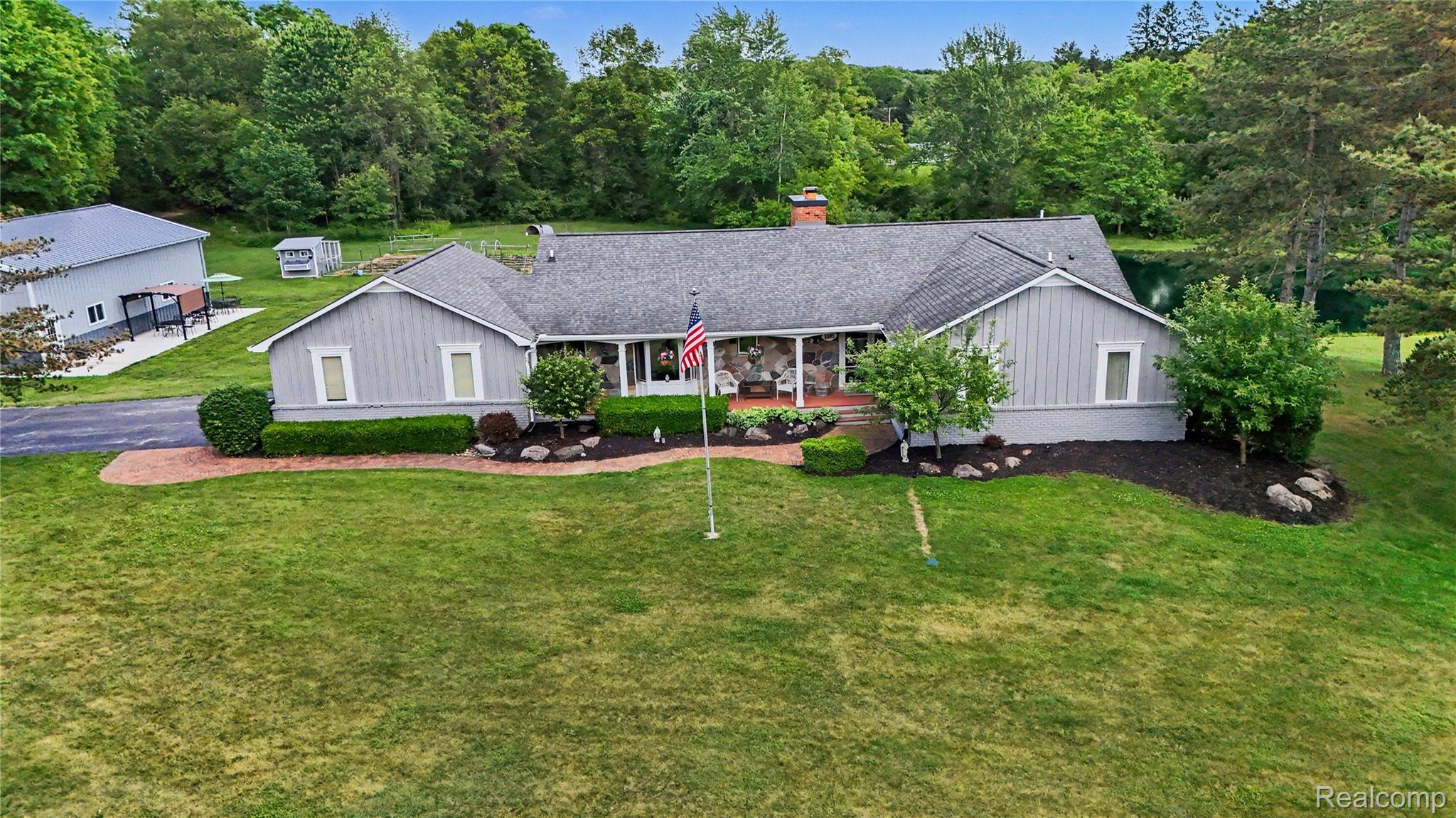 5465 South Lake George Road Metamora, MI 48455 - Photo 45 of 61 Ranch-style residence featuring a prominent stone facade, a gray shingle roof, and a red brick chimney