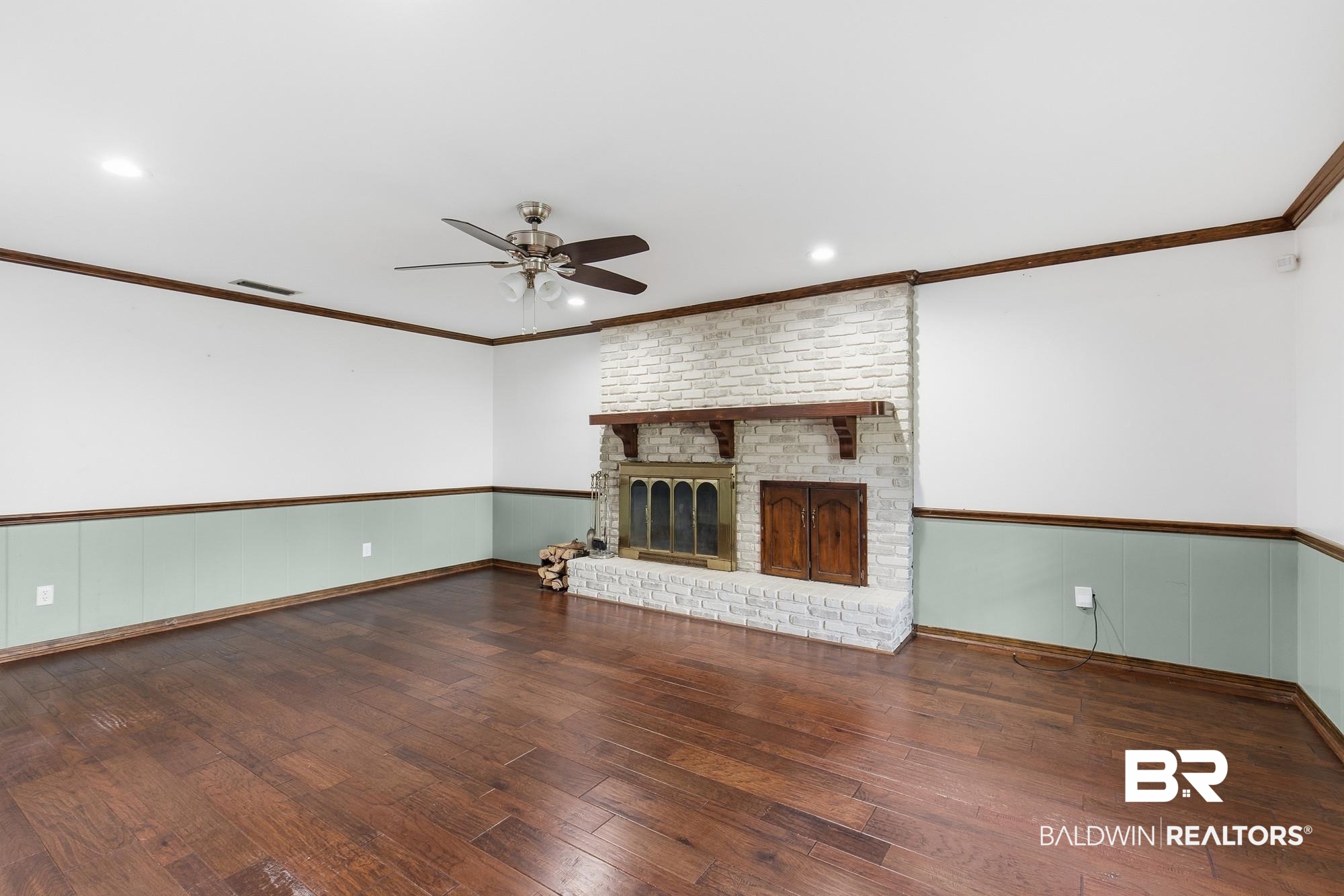 9215 Shiloh Drive Mobile, AL 36695 - Photo 12 of 32 Unfurnished living room featuring dark wood finished floors, ornamental molding, a brick fireplace, a ceiling fan, and recessed lighting