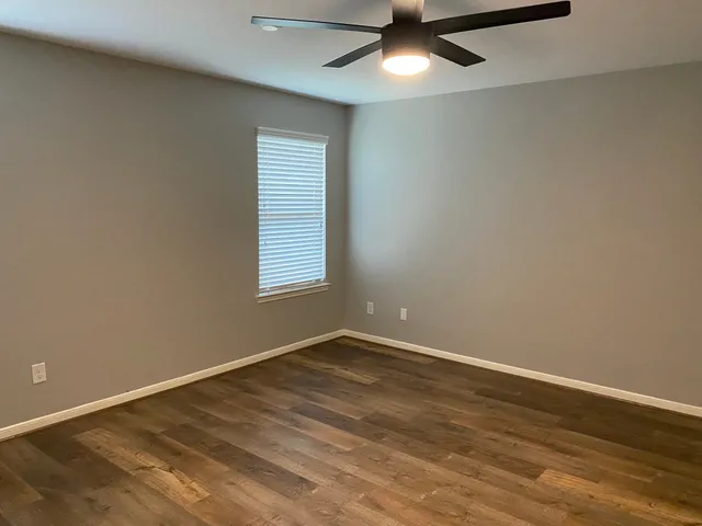 an empty room with a window and ceiling fan