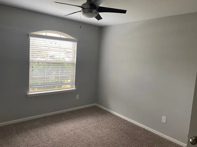 an empty room with a window and a fan