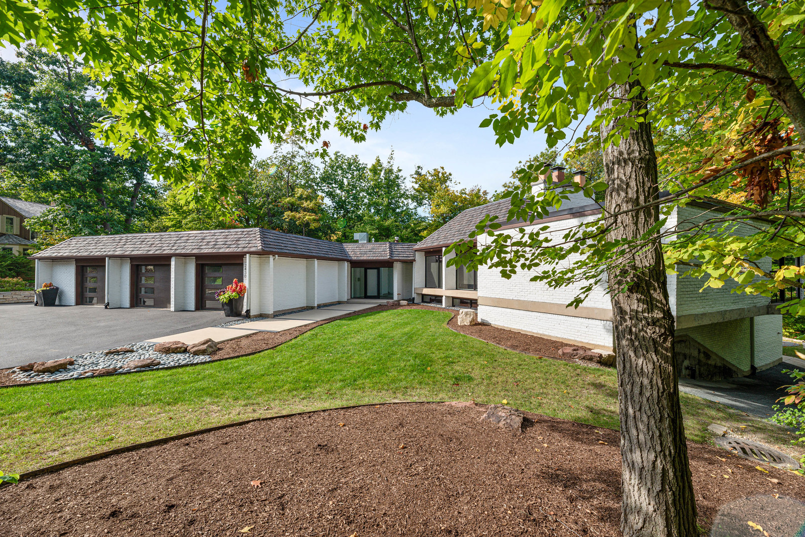 a front view of a house with a garden and trees