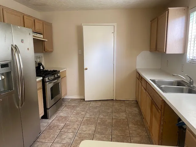 a kitchen with stainless steel appliances a refrigerator sink and stove