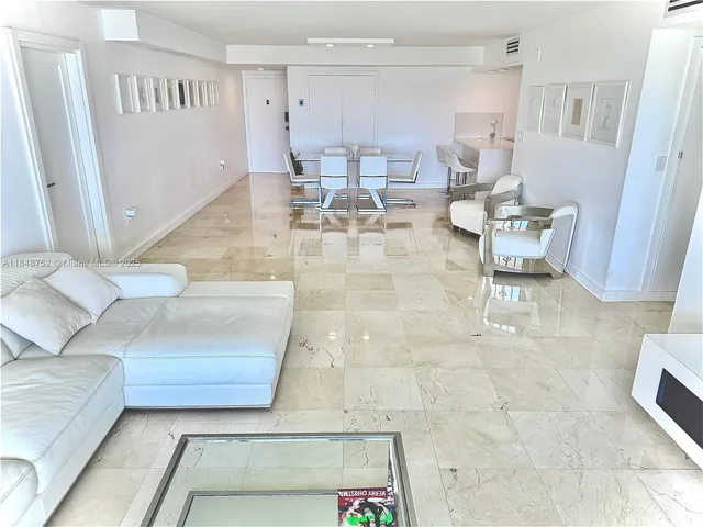 a living room with couches and kitchen view with wooden floor