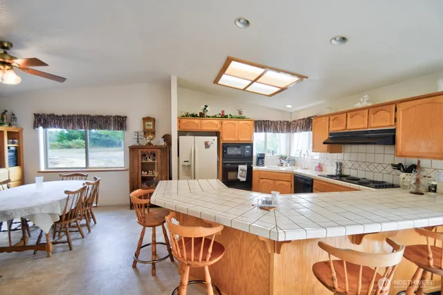 a kitchen with stainless steel appliances granite countertop a stove top oven a sink a dining table and chairs with wooden floor