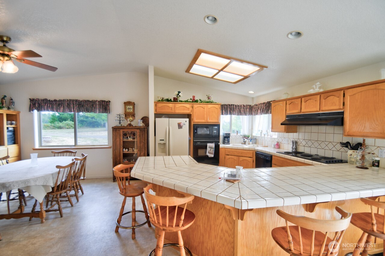 378 Burnt Ridge Road Onalaska, WA 98570 - Photo 9 of 40 a kitchen with stainless steel appliances granite countertop a stove top oven a sink a dining table and chairs with wooden floor