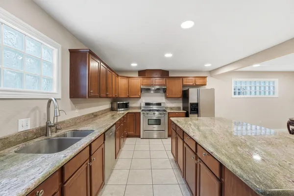 a large kitchen with stainless steel appliances granite countertop a sink counter space cabinets and a large window