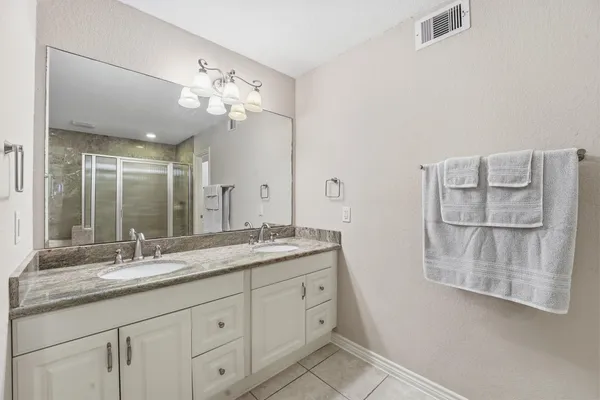 a bathroom with a granite countertop double vanity sink and mirror