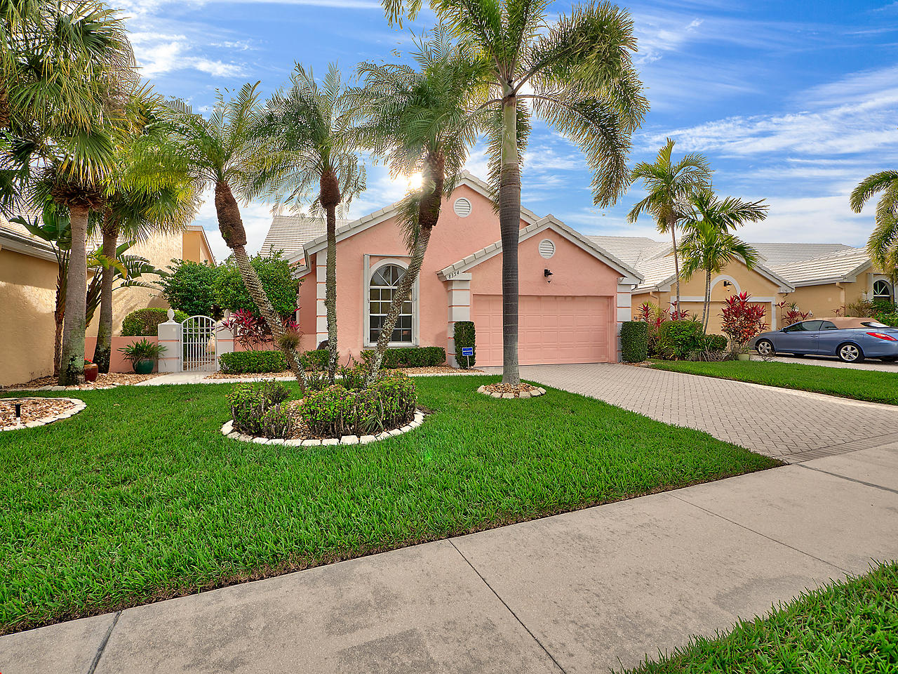 a front view of a house with a garden and palm trees