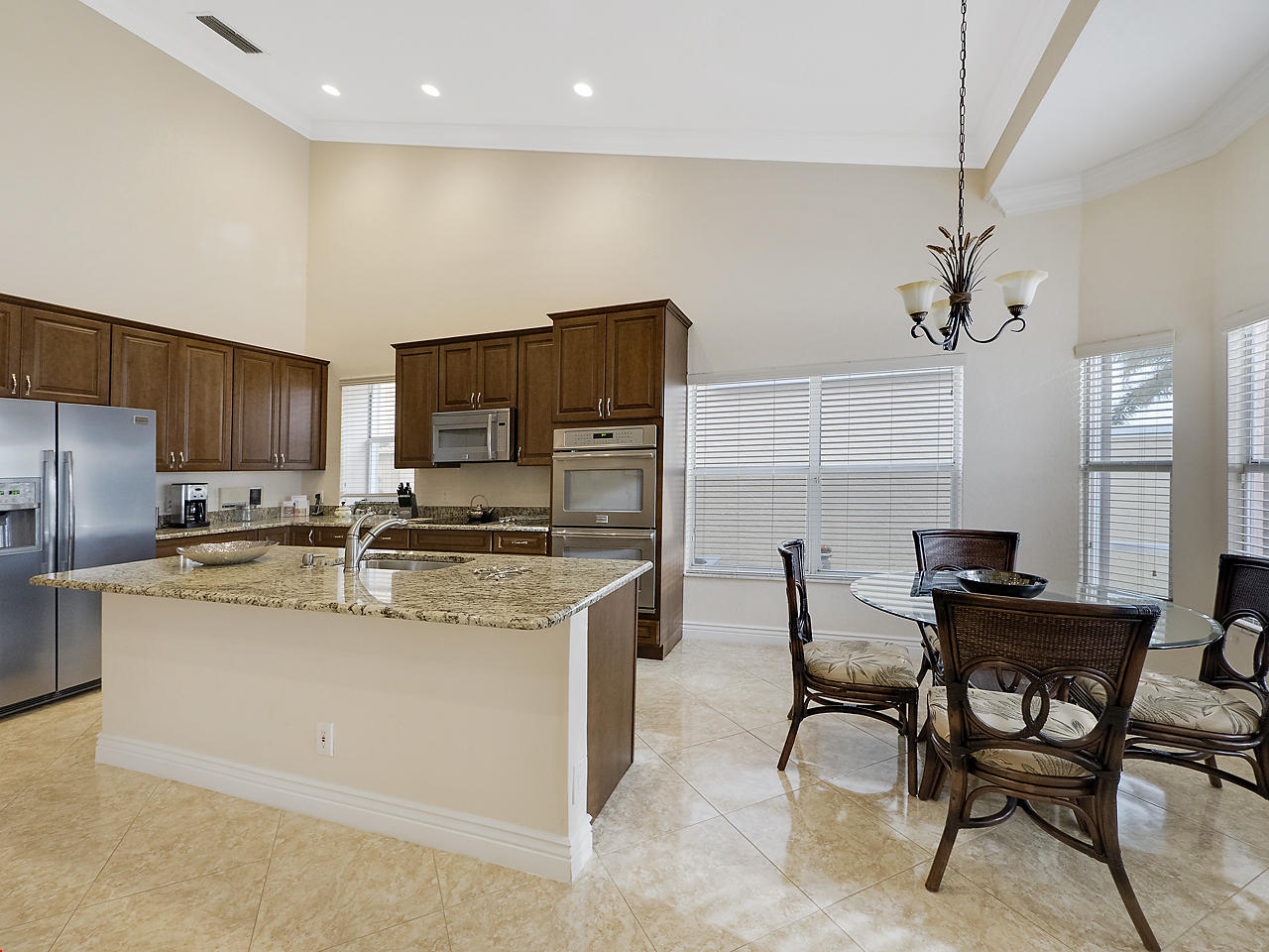 8354 Horseshoe Bay Road Boynton Beach, FL 33472 - Photo 5 of 13 a kitchen with stainless steel appliances granite countertop a table chairs and a refrigerator