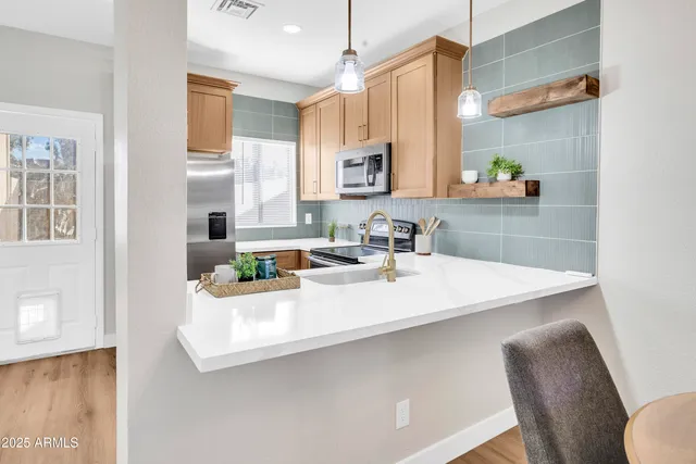 a kitchen with stainless steel appliances a sink a stove a table and chairs
