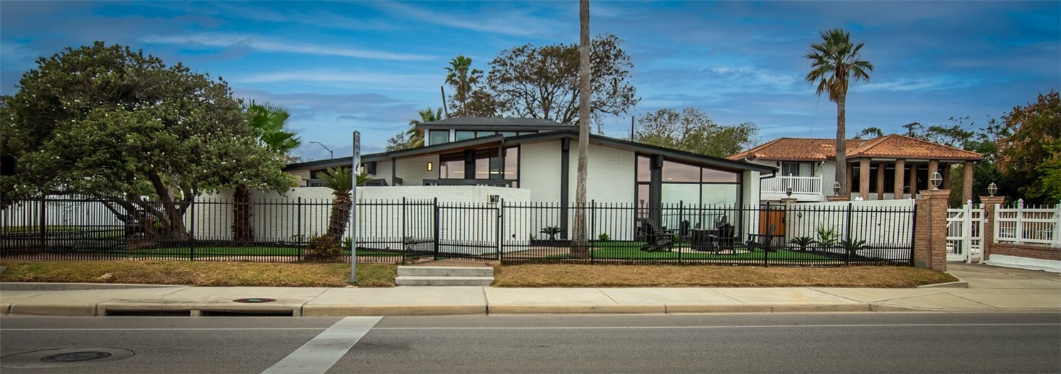 1617 Ocean Drive Corpus Christi, TX 78404 - Photo 1 of 40 a view of a white house with a yard and plants next to a road