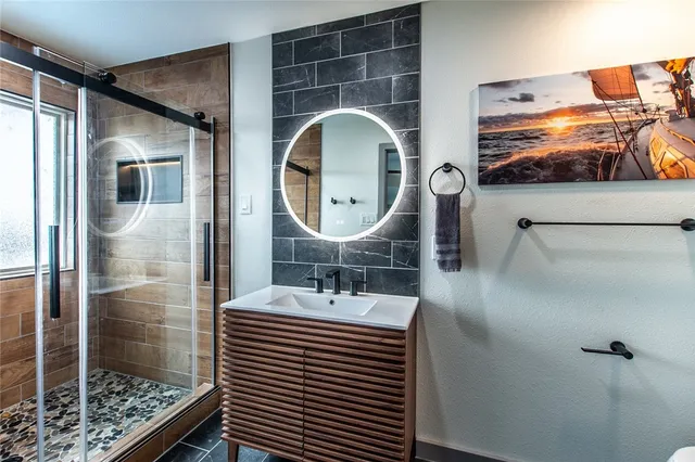 a bathroom with a sink a mirror a vanity and shower