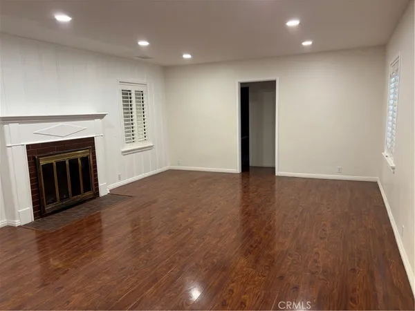 an empty room with wooden floor fireplace and windows