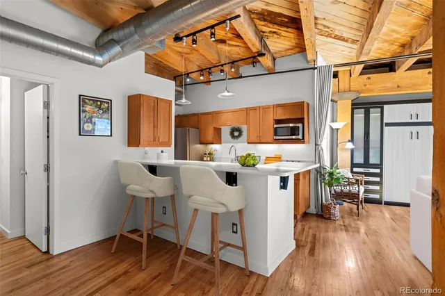 a kitchen with stainless steel appliances a white table chairs and a wooden floors