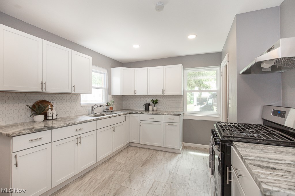 1547 Genesee Road South Euclid, OH 44121 - Photo 6 of 36 Kitchen featuring stainless steel gas range, a sink, backsplash, light stone countertops, and white cabinetry