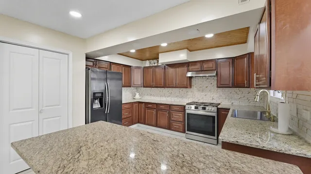 a kitchen with stainless steel appliances granite countertop a sink stove and refrigerator