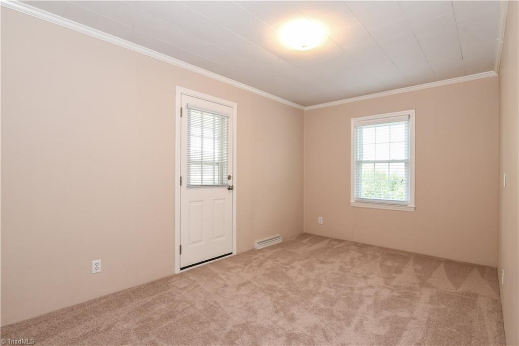 7836 Alcorn Road Oak Ridge, NC 27310 - Photo 16 of 28 Bedroom 2 - large closet (not pictured), an exterior door that leads out to a covered porch, and new carpet.