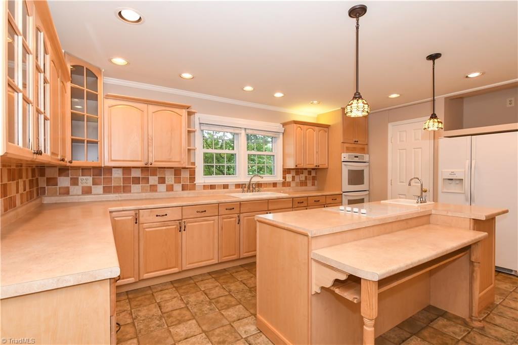 7836 Alcorn Road Oak Ridge, NC 27310 - Photo 5 of 28 Straight ahead is the door to the pantry, a niche above the refrigerator for your TV, and a breakfast bar.