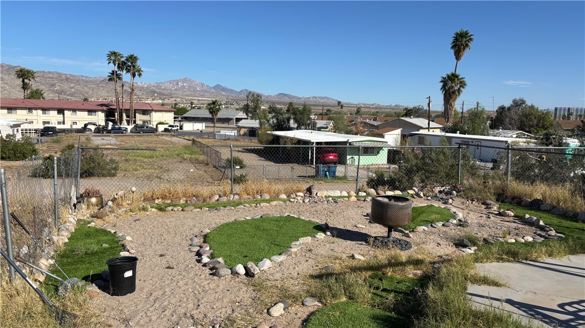 1212 Baseline Road Bullhead City, AZ 86442 - Photo 2 of 6 The property features a fenced yard with a combination of sand and grassy areas, accented by decorative rocks