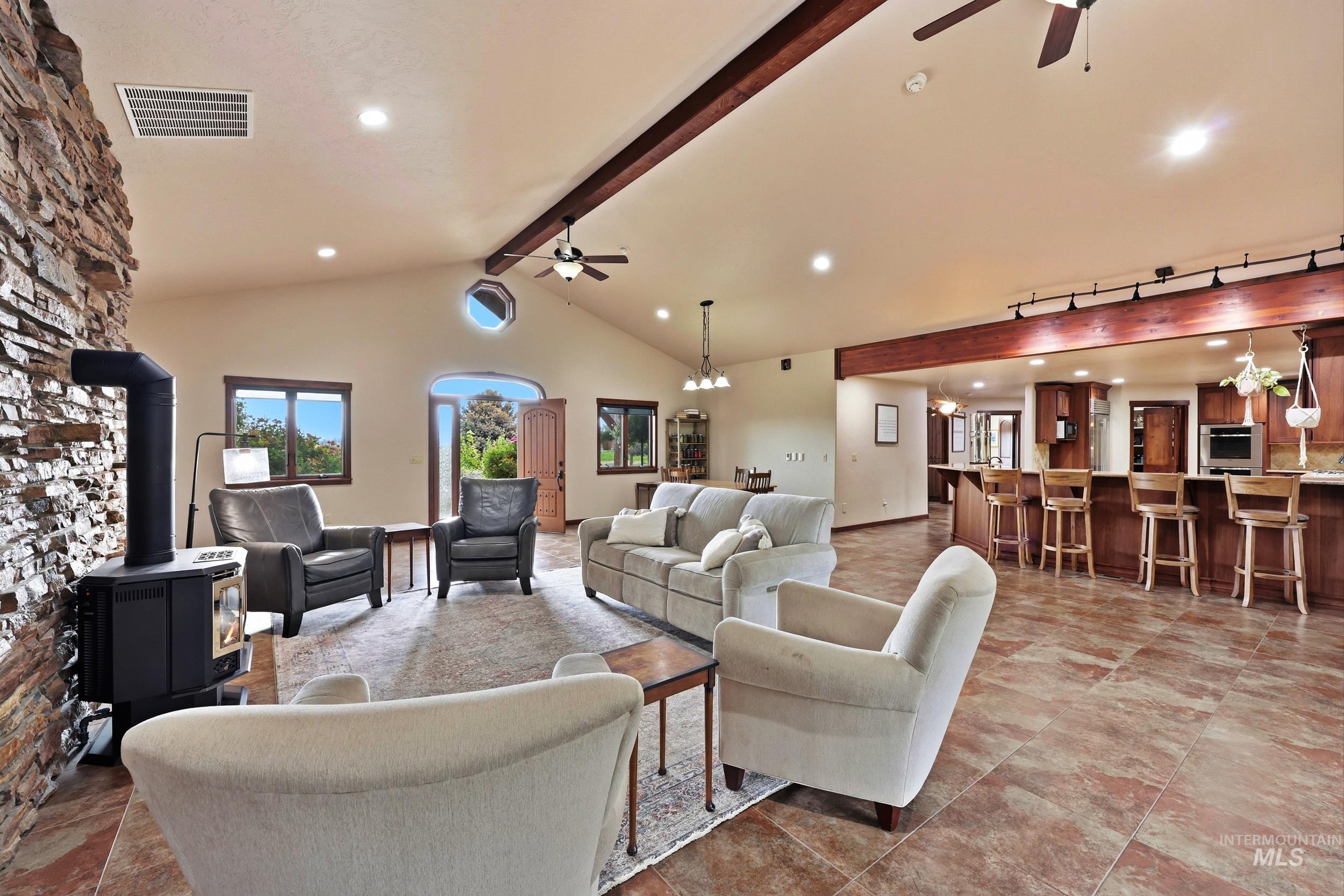 339 Airport Road Weiser, ID 83672 - Photo 7 of 49 Vaulted ceiling living space featuring a stone accent wall with a wood-burning stove, exposed wood beams, and tile flooring