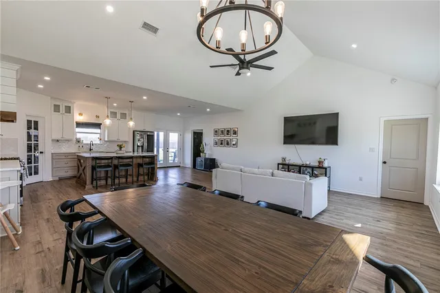a kitchen with stainless steel appliances kitchen island granite countertop a table chairs sink and cabinets