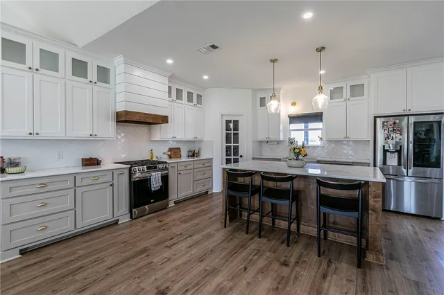 a large kitchen with stainless steel appliances granite countertop a lot of living room and wooden floors