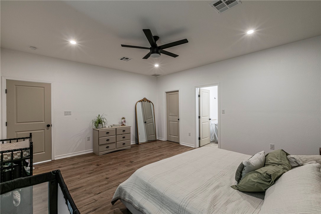 1973 Jackson Lane China Spring, TX 76633 - Photo 19 of 34 a bedroom with a bed a dresser and potted plants with wooden floor