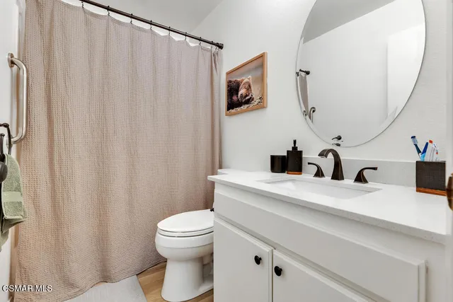 a bathroom with a granite countertop sink vanity mirror and toilet
