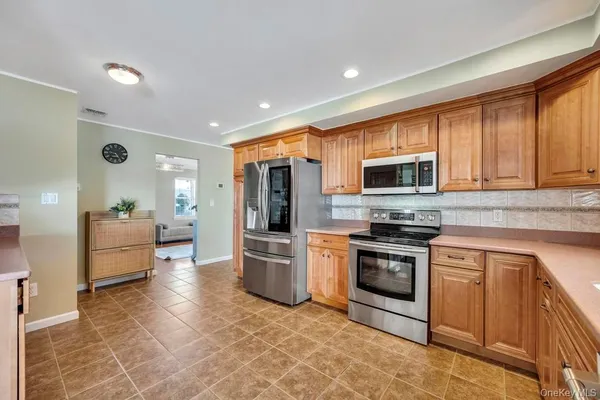 a kitchen with stainless steel appliances granite countertop a stove top oven a sink dishwasher a refrigerator and white cabinets with wooden floor