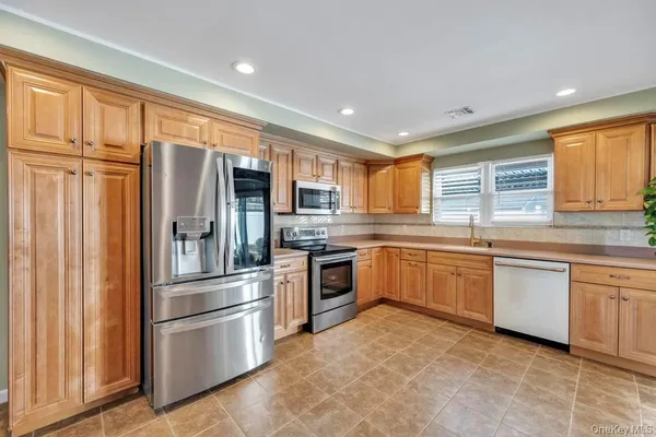 a kitchen with stainless steel appliances granite countertop a refrigerator and wooden cabinets