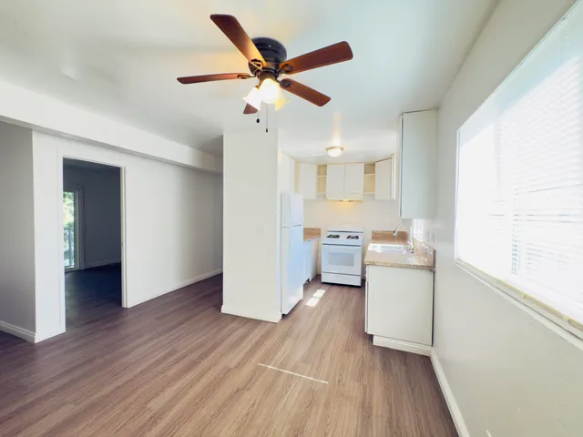 a view of a kitchen with a sink a ceiling fan and wooden floor