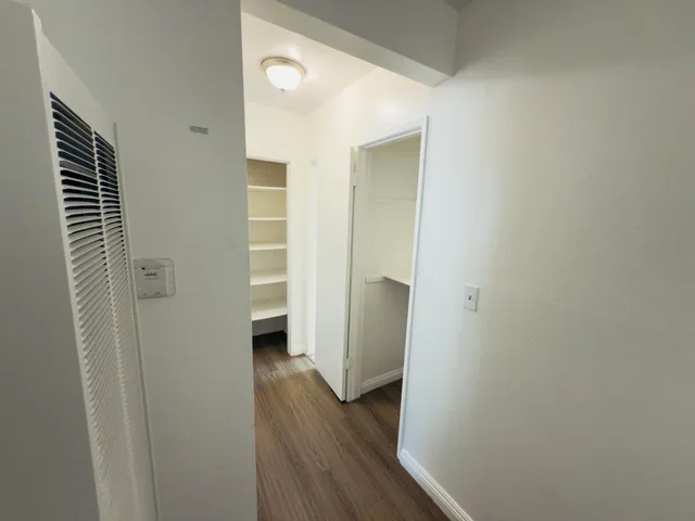 a view of a hallway with wooden floor and closet