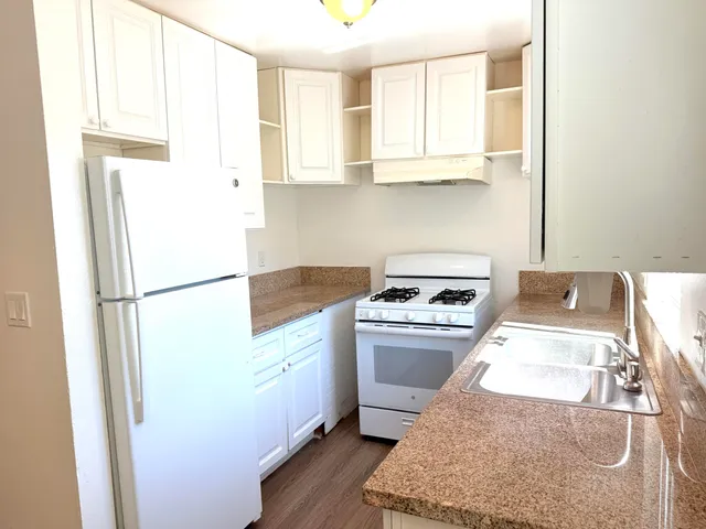 a kitchen with stainless steel appliances granite countertop a refrigerator sink stove and white cabinets