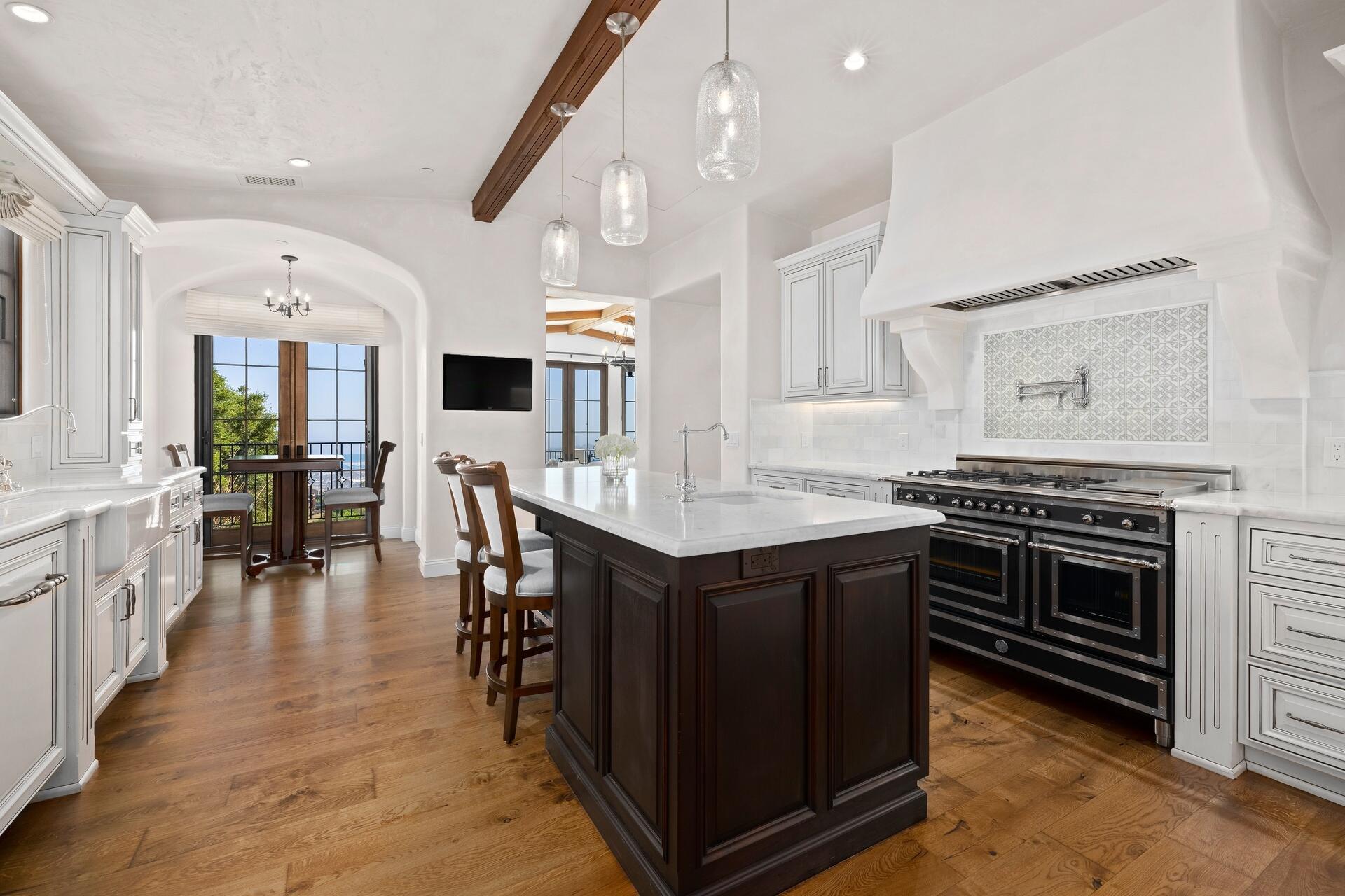 1117 Las Alturas Road Santa Barbara, CA 93103 - Photo 8 of 28 a kitchen with stainless steel appliances a stove a sink dishwasher and a dining table with wooden floor