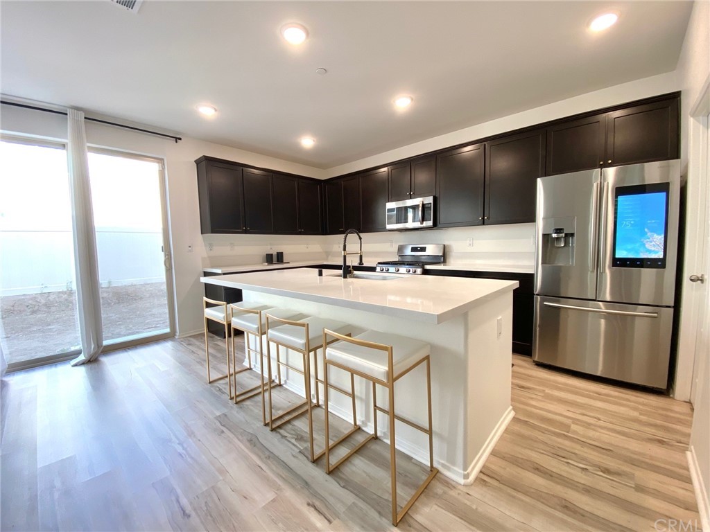 858 Blue Orchid Beaumont, CA 92223 - Photo 9 of 33 a kitchen with stainless steel appliances a sink a stove a refrigerator with wooden floor and cabinets