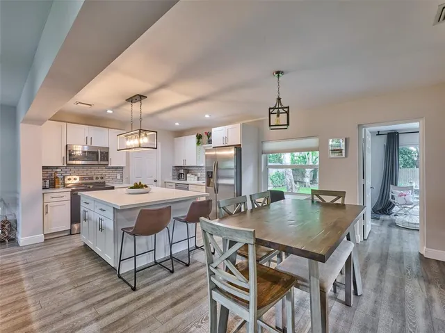 a kitchen with a dining table chairs and refrigerator