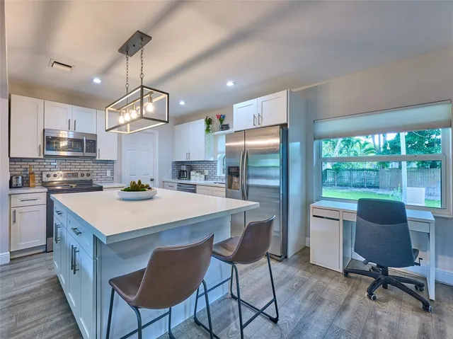 a kitchen with kitchen island a refrigerator a stove a dining table and chairs with wooden floor