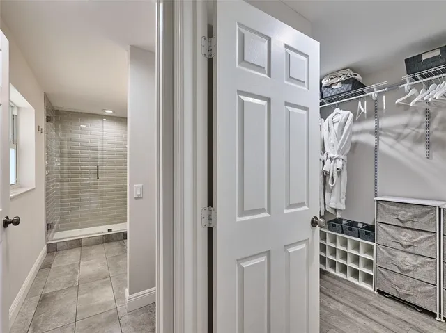 a view of a hallway with wooden floor and a bathroom
