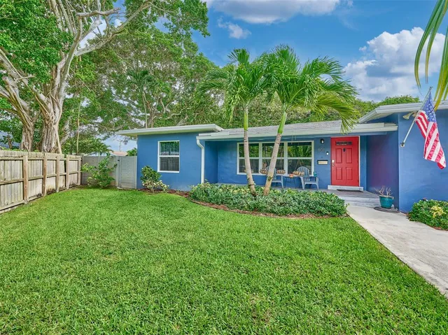 a view of a brick house with a big yard plants and large trees