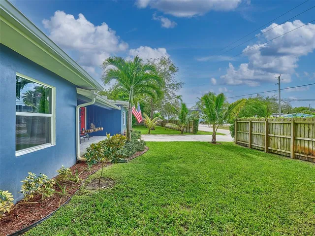 a view of a house with a yard and a large tree
