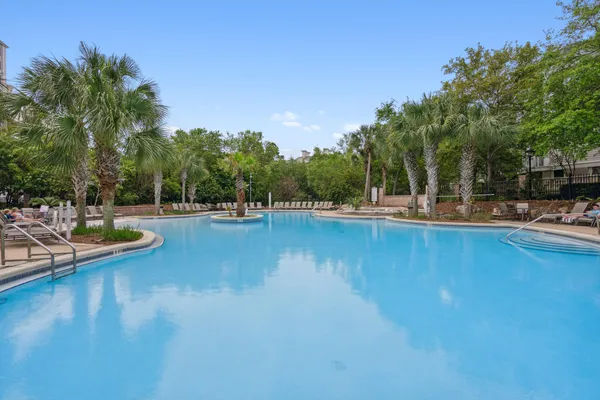 a view of a swimming pool with outdoor seating and trees in the background