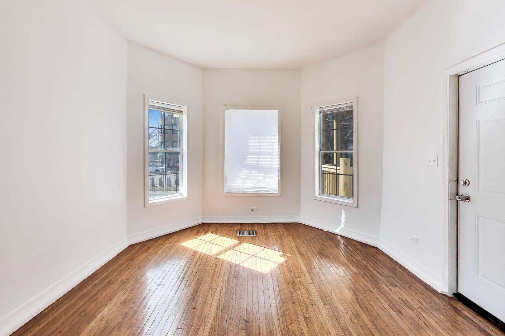 6853 South Perry Avenue Chicago, IL 60621 - Photo 6 of 28 an empty room with wooden floor and windows