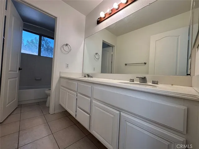a spacious bathroom with a double vanity sink a mirror and a bathtub