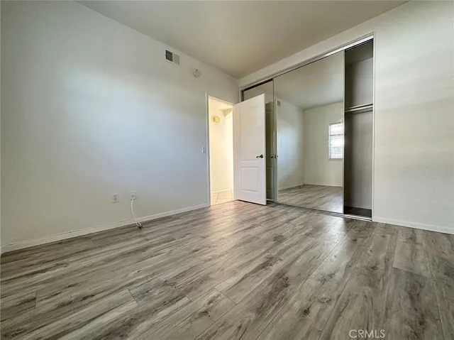 a view of an empty room with wooden floor and closet