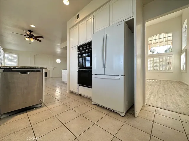 a view of a refrigerator in kitchen and an empty room in wooden floor
