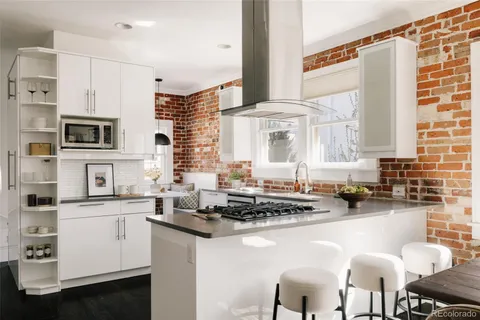 a kitchen with stainless steel appliances a sink a stove a refrigerator cabinets and chairs