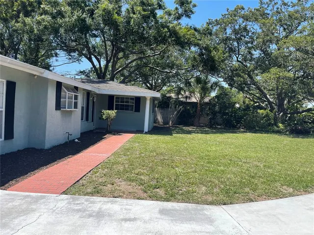 a backyard of a house with large trees and plants
