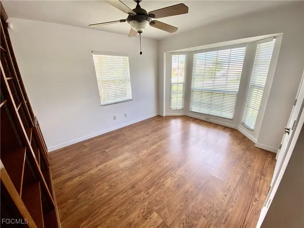 an empty room with wooden floor fan and windows