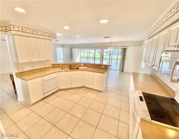 a large white kitchen with a sink a counter top space and cabinets