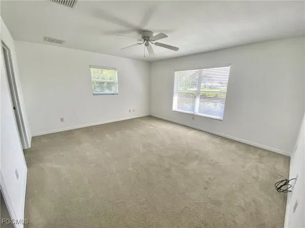 an empty room with a ceiling fan and window